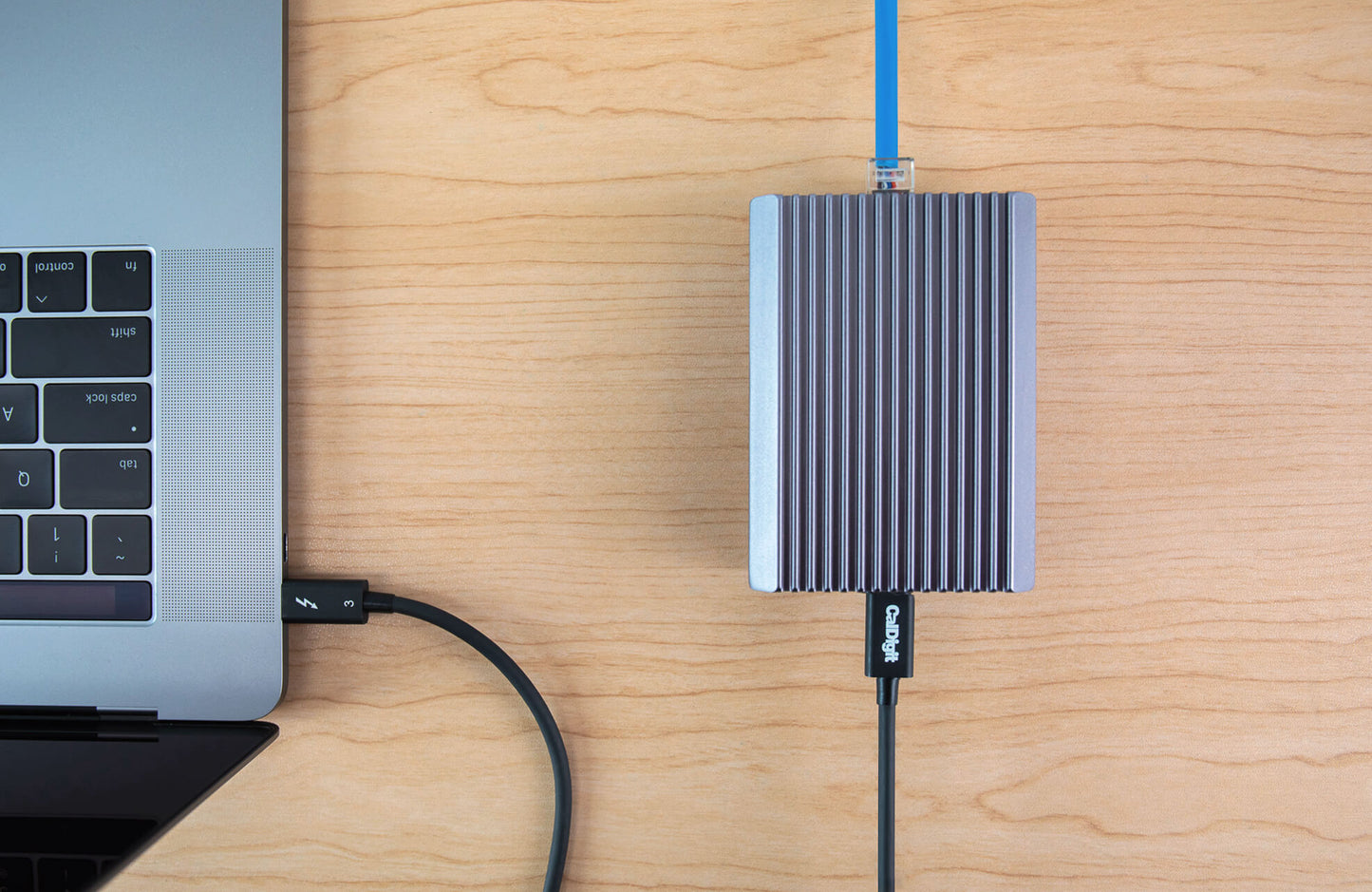 An overhead image of a Connect-10G on a desk connected via Thunderbolt to a computer on one side, and to ethernet on the other side.