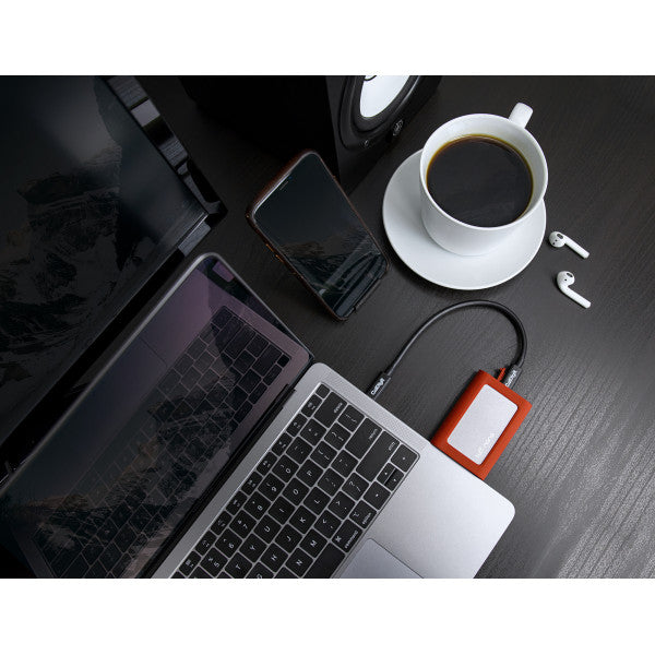 Tuff nano on a desk connected to a laptop. On the desk there is a cup of coffee, an iPhone and wireless headphones.